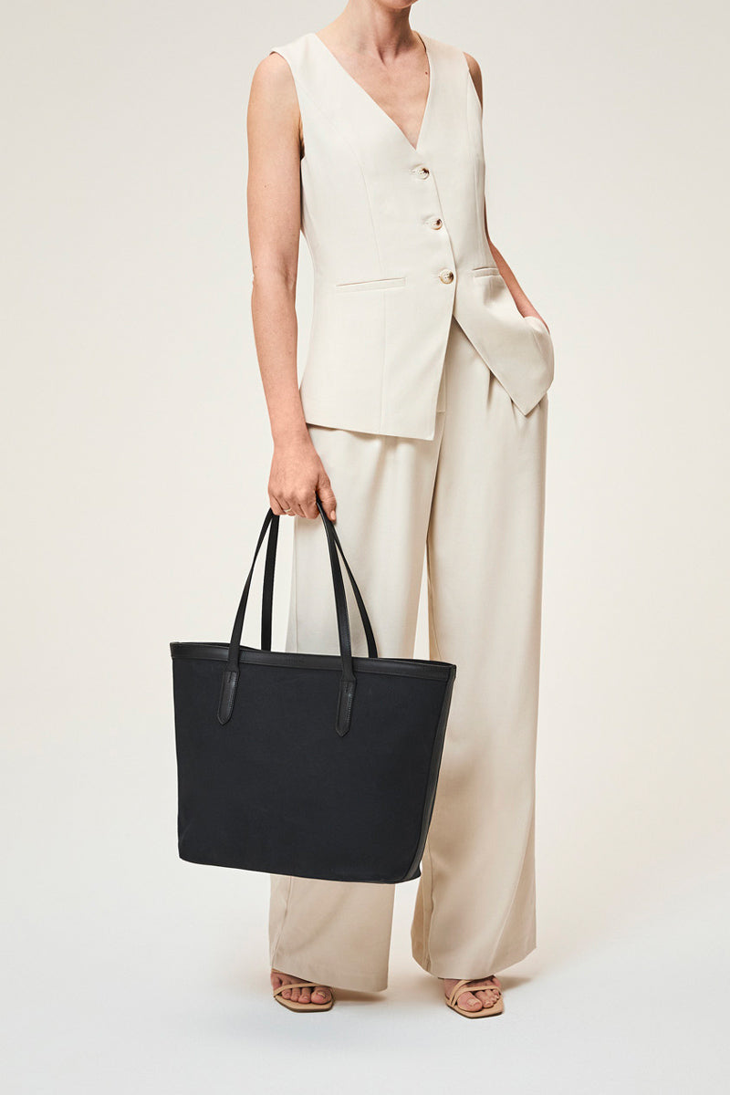 Black TUSTING canvas tote bag with shoulder straps, showing the spacious interior and stylish design.