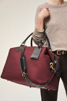 Medium TUSTING Superlight Explorer top handle bag in black, showing its sleek design and sturdy handle on a plain background.