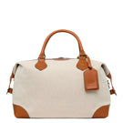 TUSTING COMO Explorer medium top handle bag in brown leather with gold hardware and adjustable strap on a plain background.