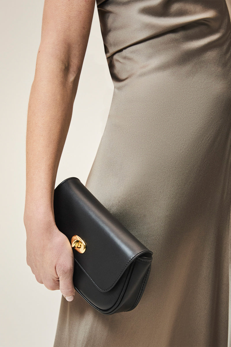 Black TUSTING Hettie clutch bag with sleek design, featuring a smooth finish and compact size for versatile elegance.