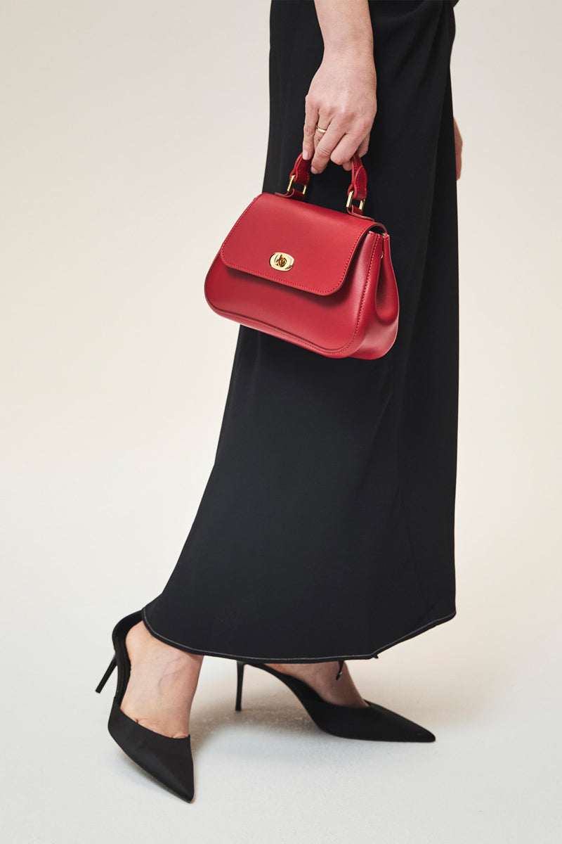 TUSTING Mini Holly in Crimson top handle bag with gold hardware, featuring a structured design and sleek crimson leather finish.