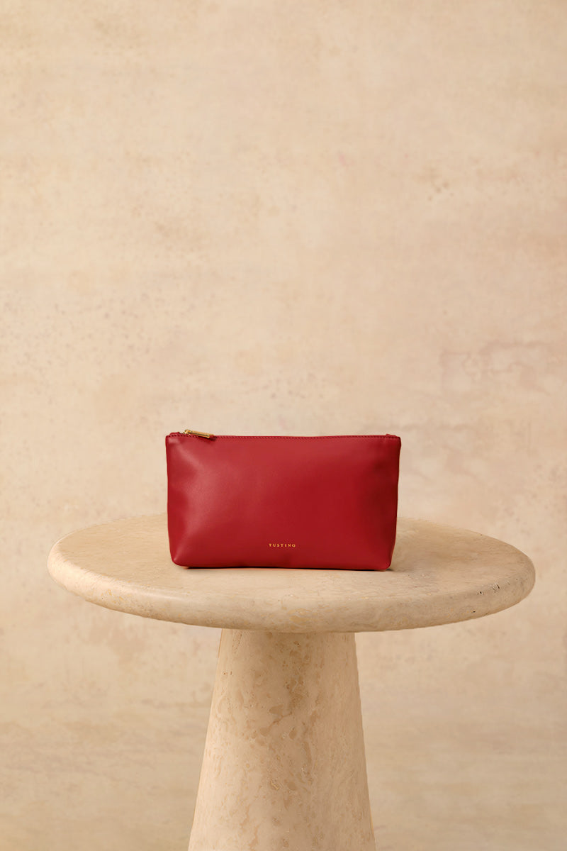 Crimson leather top handle pouch bag by TUSTING with a sleek, compact design and a sturdy top handle.