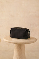 TUSTING Horizon clutch with black leather trim and Como canvas, featuring a sleek, compact design and stylish black accents.