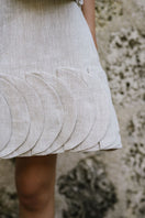Light beige TATTI mini skirt by ANA + MARIA, shown in a campaign photo, styled with a casual top and accessories.