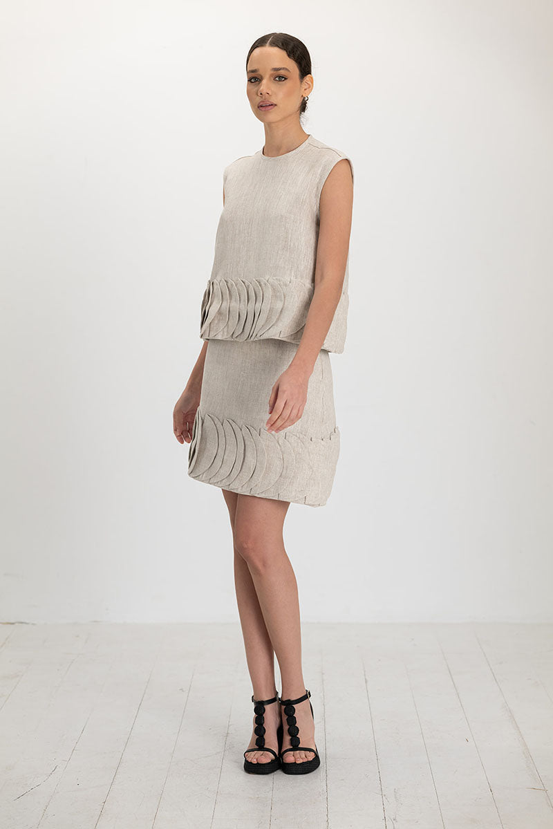Beige TATTI mini skirt by ANA + MARIA in sand color, with a fitted waist and stylish design, shown on a model.