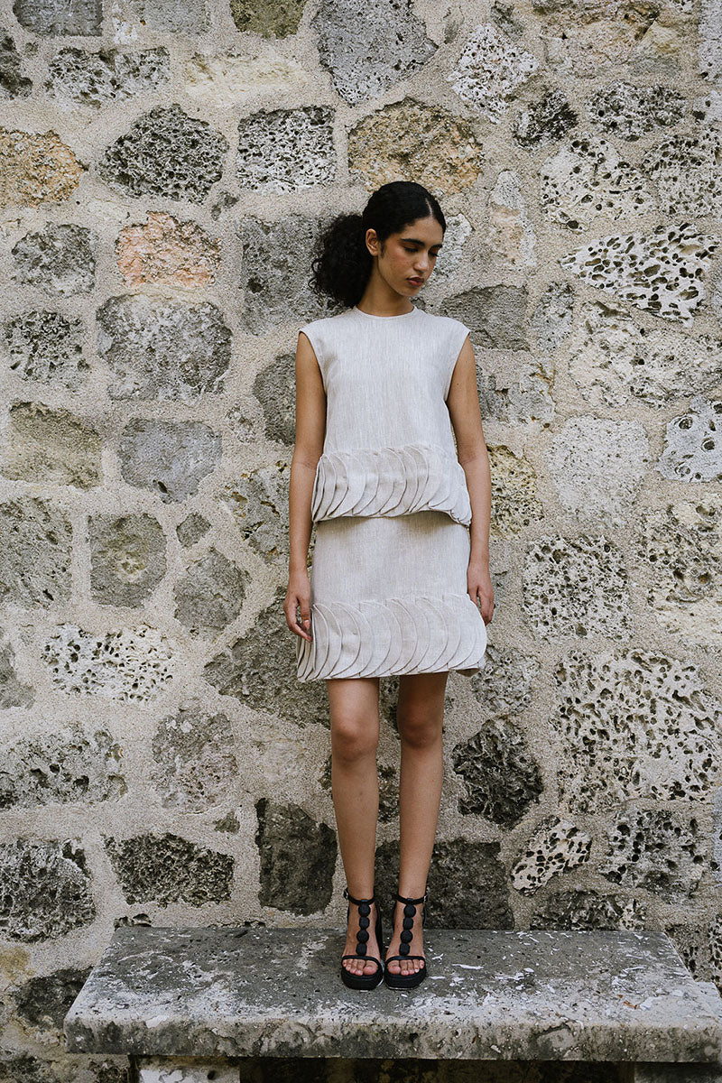 ANA + MARIA TATTI top in sand, stylish sleeveless blouse with a relaxed fit, shown in a fashion campaign photo.