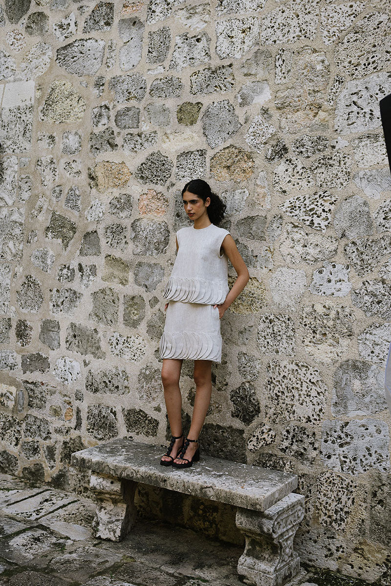 Ana + Maria Tatti top in sand, stylish sleeveless blouse with a relaxed fit, shown in a fashion campaign photo.