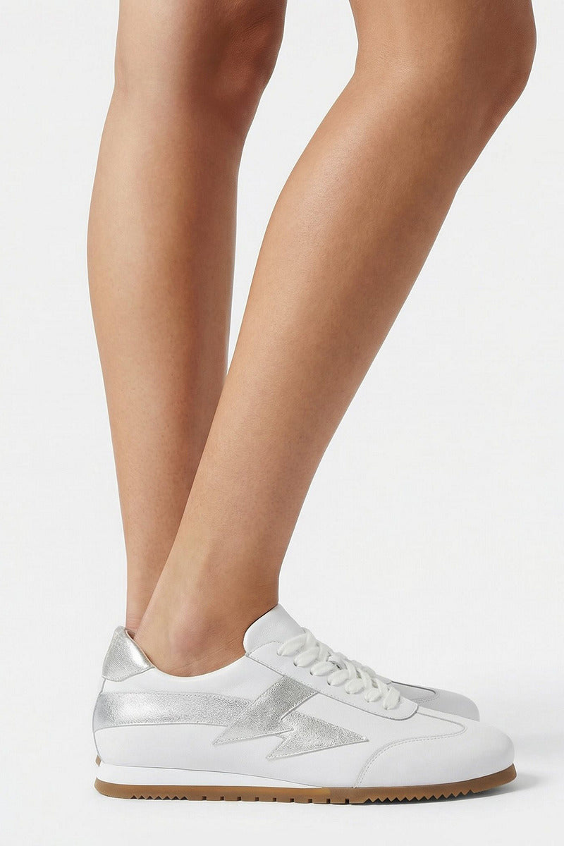 White Terry de Havilland jogger bolt flats with sleek design and smooth leather finish, shown on a model's legs.