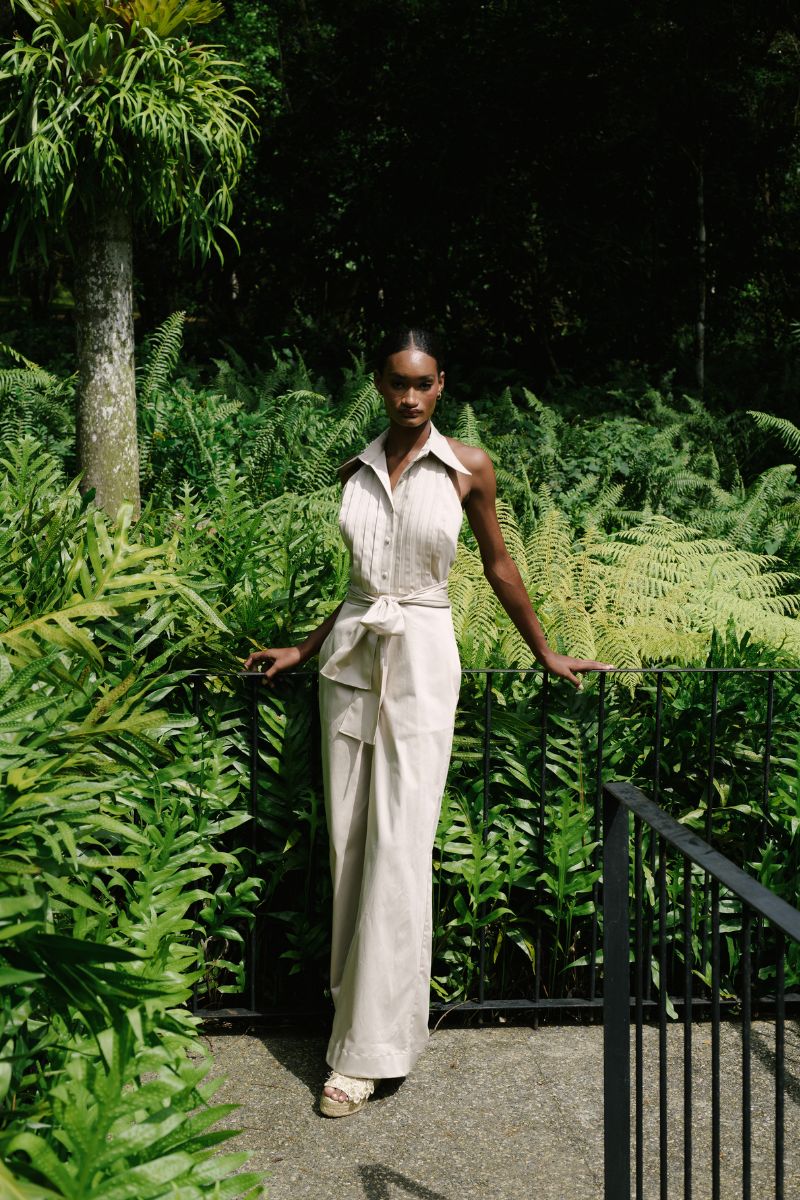 ANA + MARIA wrapped jumpsuit in sand color, featuring a stylish design, displayed on a model in a fashion campaign photo.