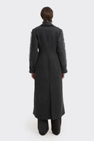 Black Thread Coat by Stolen Stores, stylish outerwear with a sleek design, shown on a model with a modern urban background.