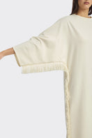 Ivory white maxi dress with long sleeves and fringe details from Stolen Stores, featuring a flowing, elegant design.
