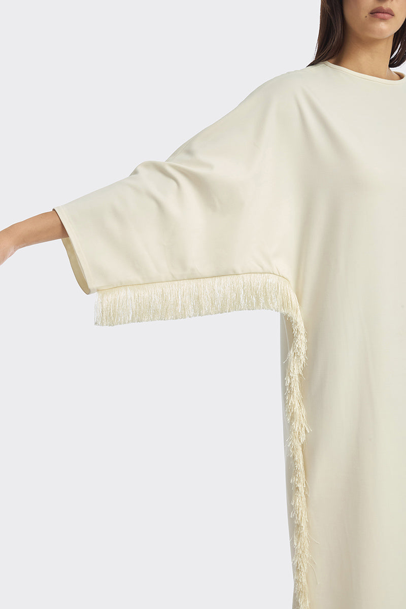 Ivory white maxi dress with long sleeves and fringe details from Stolen Stores, featuring a flowing, elegant design.