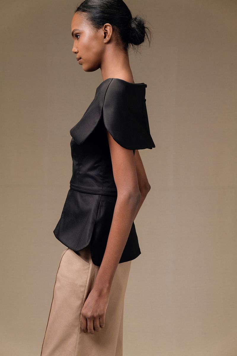 Black Tibet Top by ANA + MARIA, featuring a stylish sleeveless design with a high neckline, showcased on a model.
