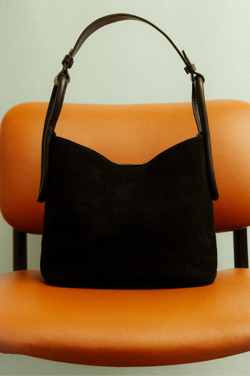 ISIDORA MALVA Tierranueva tote bag in black suede with top handle and sleek design, showcasing its stylish and soft material.