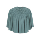 Hand-smocked TIYA cape in Saxon color by MASTANI, featuring intricate detailing and a stylish top design.