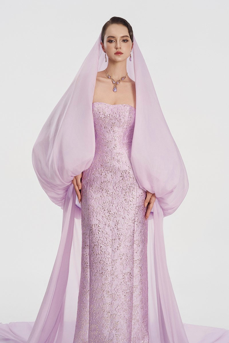 Elegant jacquard gown with a hooded veil cape by Tracy Studio, featuring intricate patterns and flowing maxi dress design.