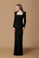 Black crepe de chine silk-lined gown by I.H.F with trapeze neckline, long sleeves, and elegant green crystal details.