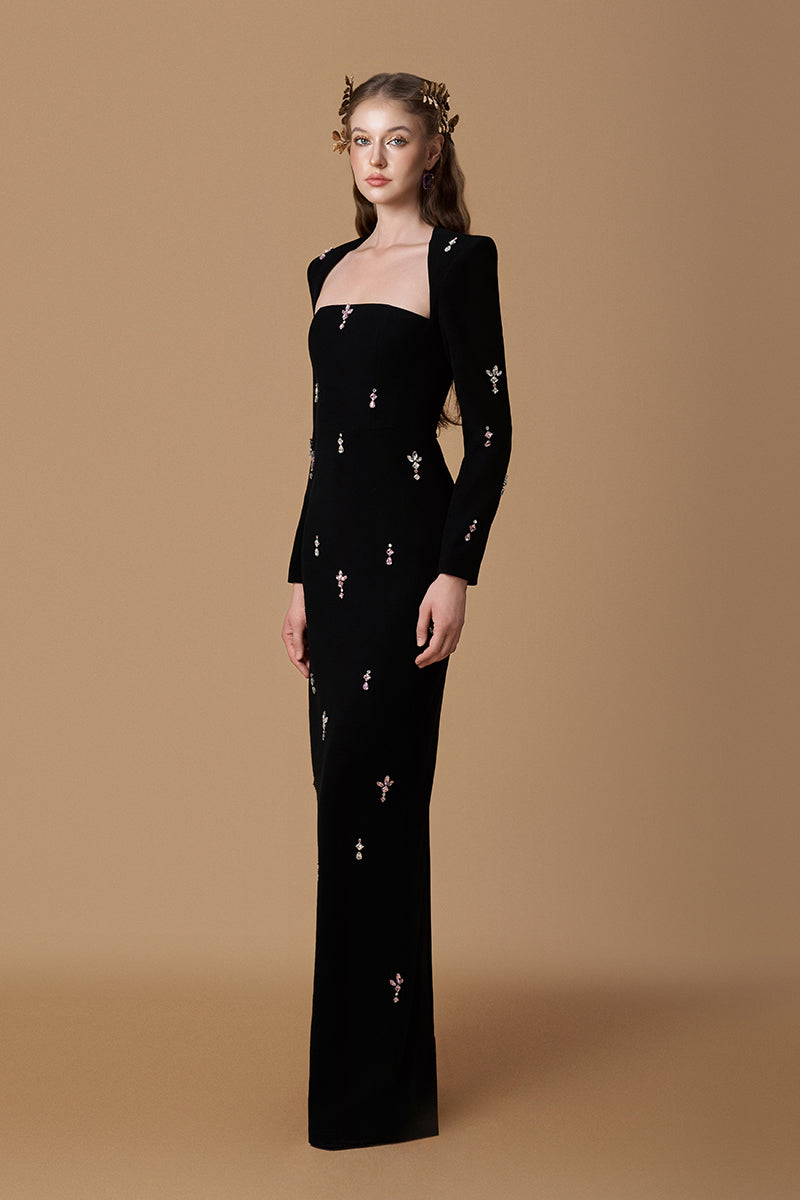 Black crepe maxi dress by I.H.F with a trapeze neckline, long sleeves, and pink stones detail, designed for elegant occasions.