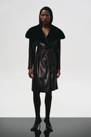 Brown leather trench coat with a fur collar by Kris Marán, featuring a classic design and stylish detailing.