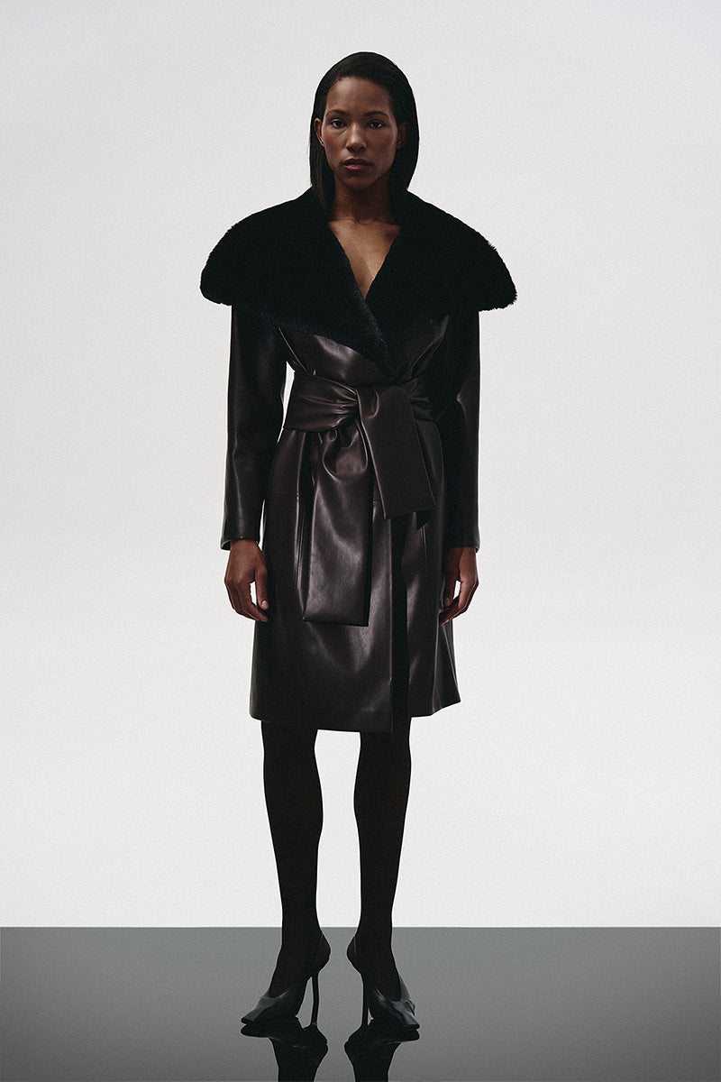 Brown leather trench coat with a fur collar by Kris Marán, featuring a classic design and stylish detailing.