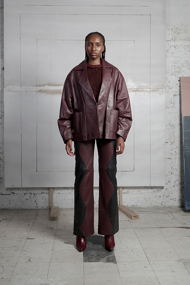 Black and wine red two-tone leather mountain trousers by MAZ Manuela Álvarez, stylish and modern pants with contrasting colors.