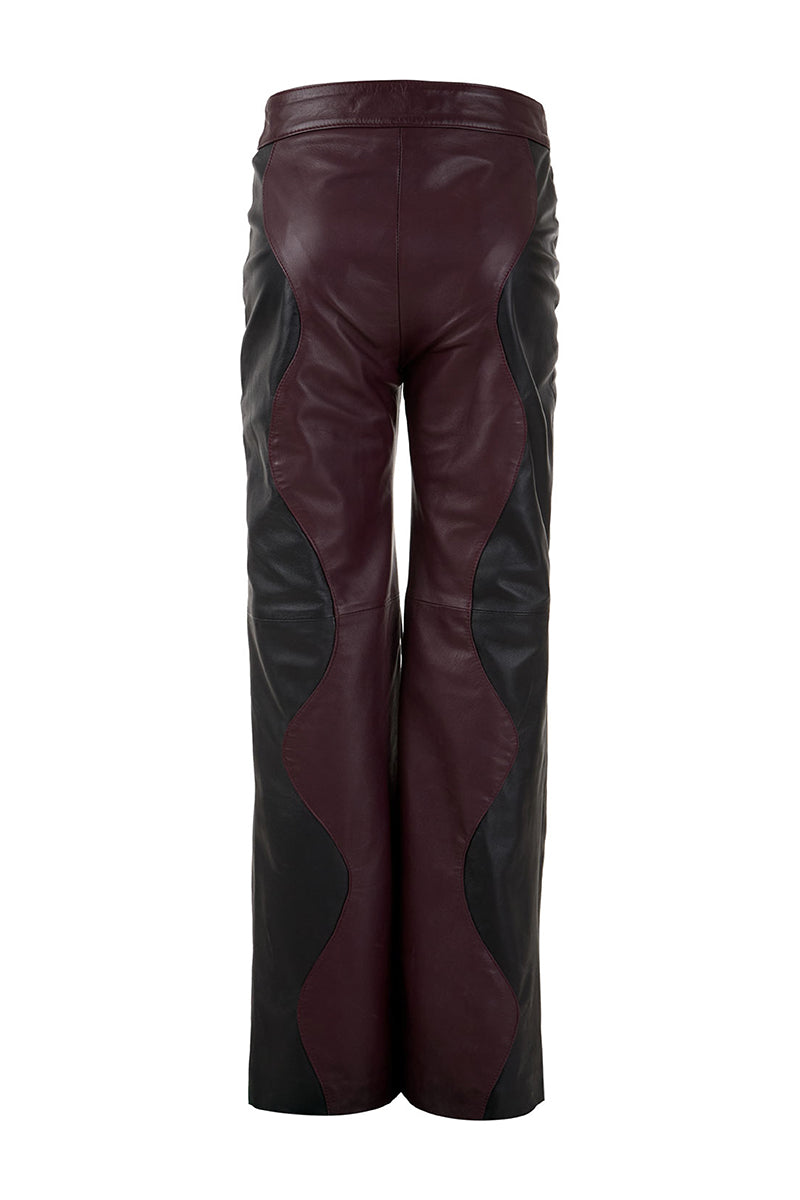 Black and wine red two-tone leather trousers by MAZ Manuela Álvarez with mountain-inspired design and tailored fit.