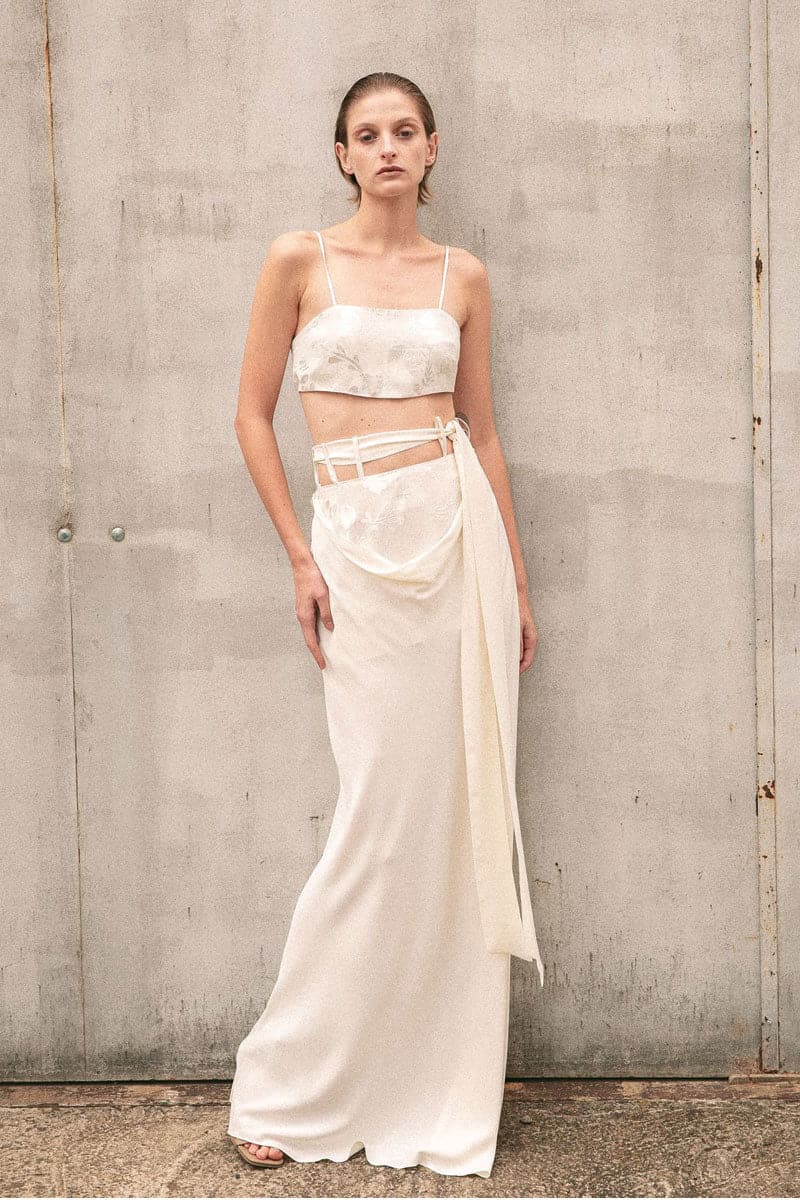 Beige Vaska crop top with short sleeves and fitted design, styled on a model against a neutral background.