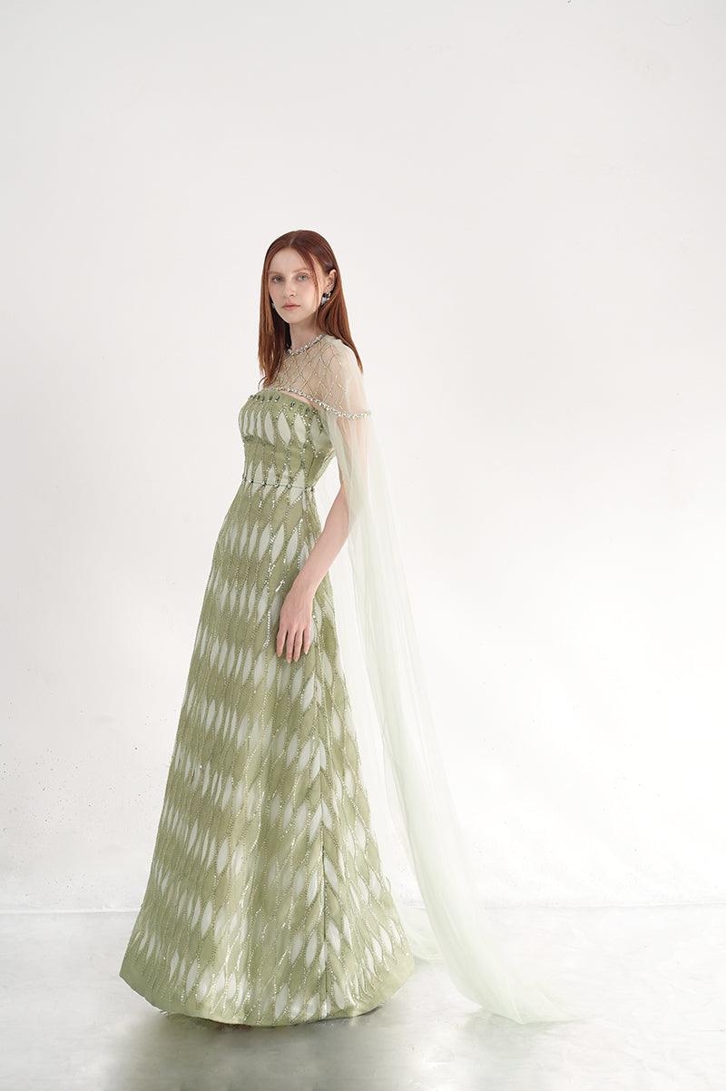 Embellished dusty mesh gown with cape by Happy Clothing, featuring intricate details and flowing fabric for elegant evening wear.