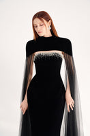 Black velvet gown with cape details by Happy Clothing, featuring a flowing silhouette and elegant design for formal occasions.