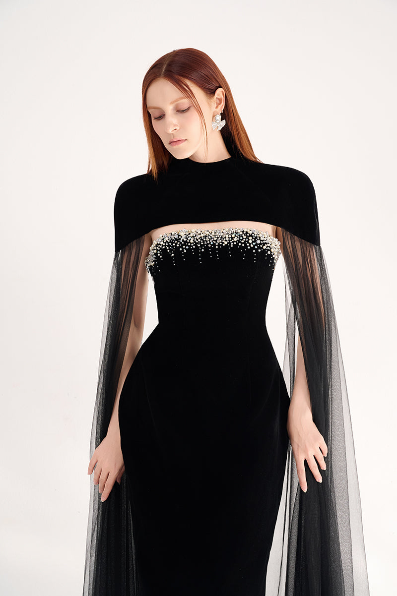 Black velvet gown with cape details by Happy Clothing, featuring a flowing silhouette and elegant design for formal occasions.