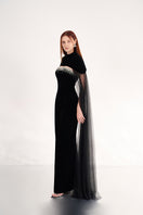 Black velvet gown with cape details, elegant evening dress by Happy Clothing, featuring flowing fabric and sophisticated design.