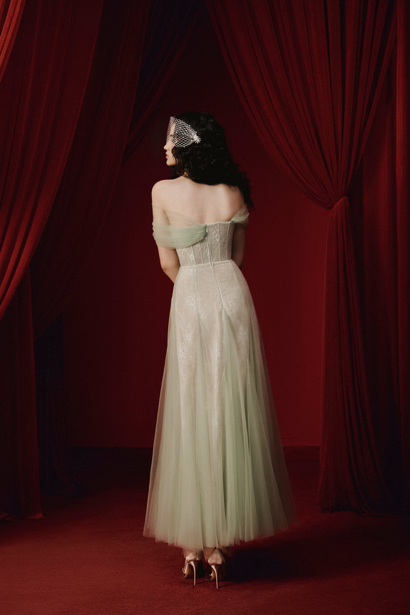 Green TINLEY dress gown by JOSÉPHINE, displayed on a hanger with detailed fabric and elegant design elements.