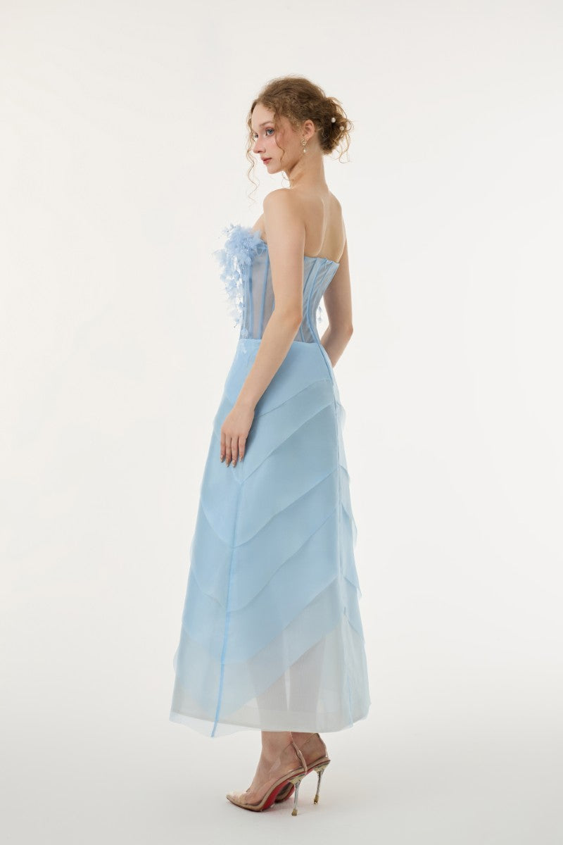 Light blue Coralie tulle and organza maxi dress by 21Six, featuring flowing fabric and elegant design, displayed on a dress form.