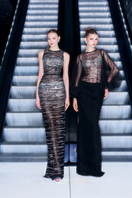 Black stripe beaded gown by CEM featuring intricate beadwork and flowing fabric, shown hanging on a plain background.
