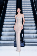Elegant Champagne Illusion gown by CEM featuring delicate lace details and a flowing silhouette.