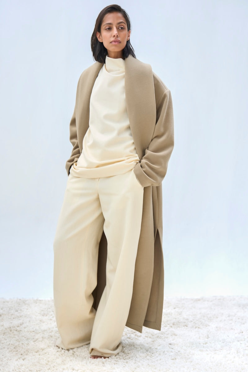 URAA ISA coat in neutral fabric shown on a hanger, featuring a classic design and tailored fit.
