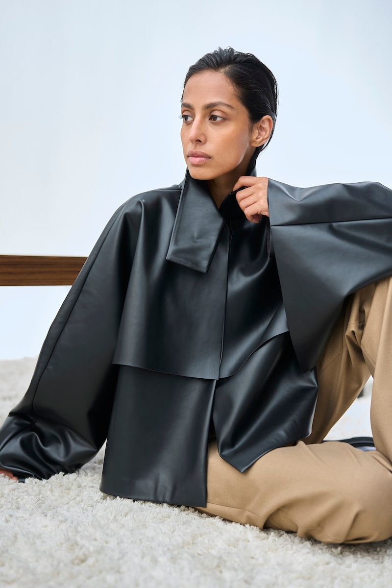 Black URA PIA trench jacket with classic design, featuring a tailored fit and stylish collar, displayed on a hanger.