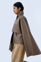 Black URA PIA trench jacket with classic collar and button closure, displayed on a hanger.