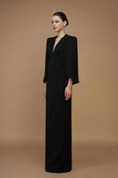 Black emerald gown by I.H.F with crepe and silk lining, featuring a V-neck, column silhouette, and cape sleeves.
