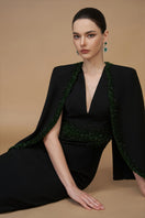 Black emerald gown by I.H.F featuring a V-neck, crepe and silk lining, and elegant cape sleeves.