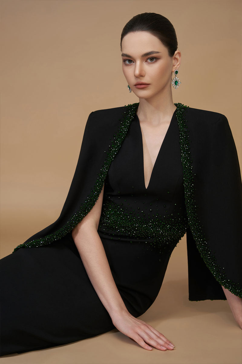 Black emerald gown by I.H.F featuring a V-neck, crepe and silk lining, and elegant cape sleeves.