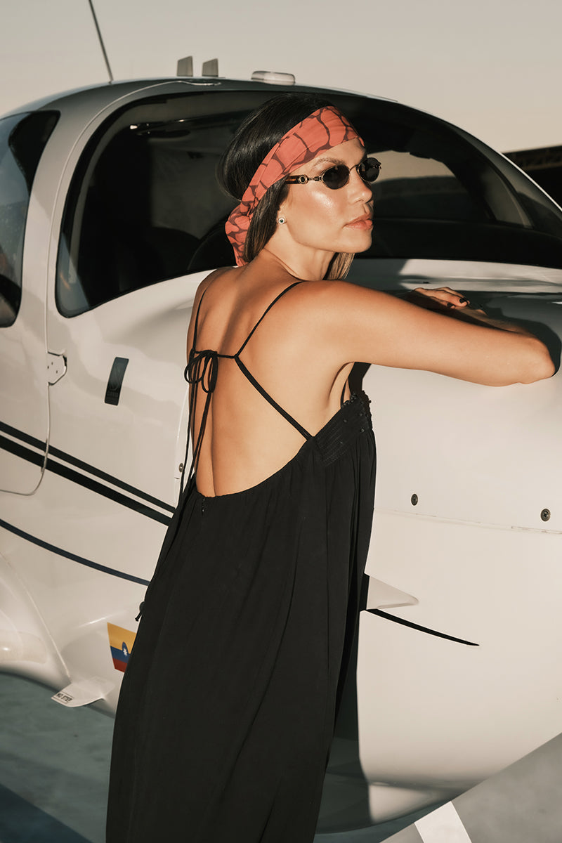 DUMA&CO Resonancia Maxi Dress in flowing fabric with a vibrant pattern, displayed on a hanger against a neutral background.