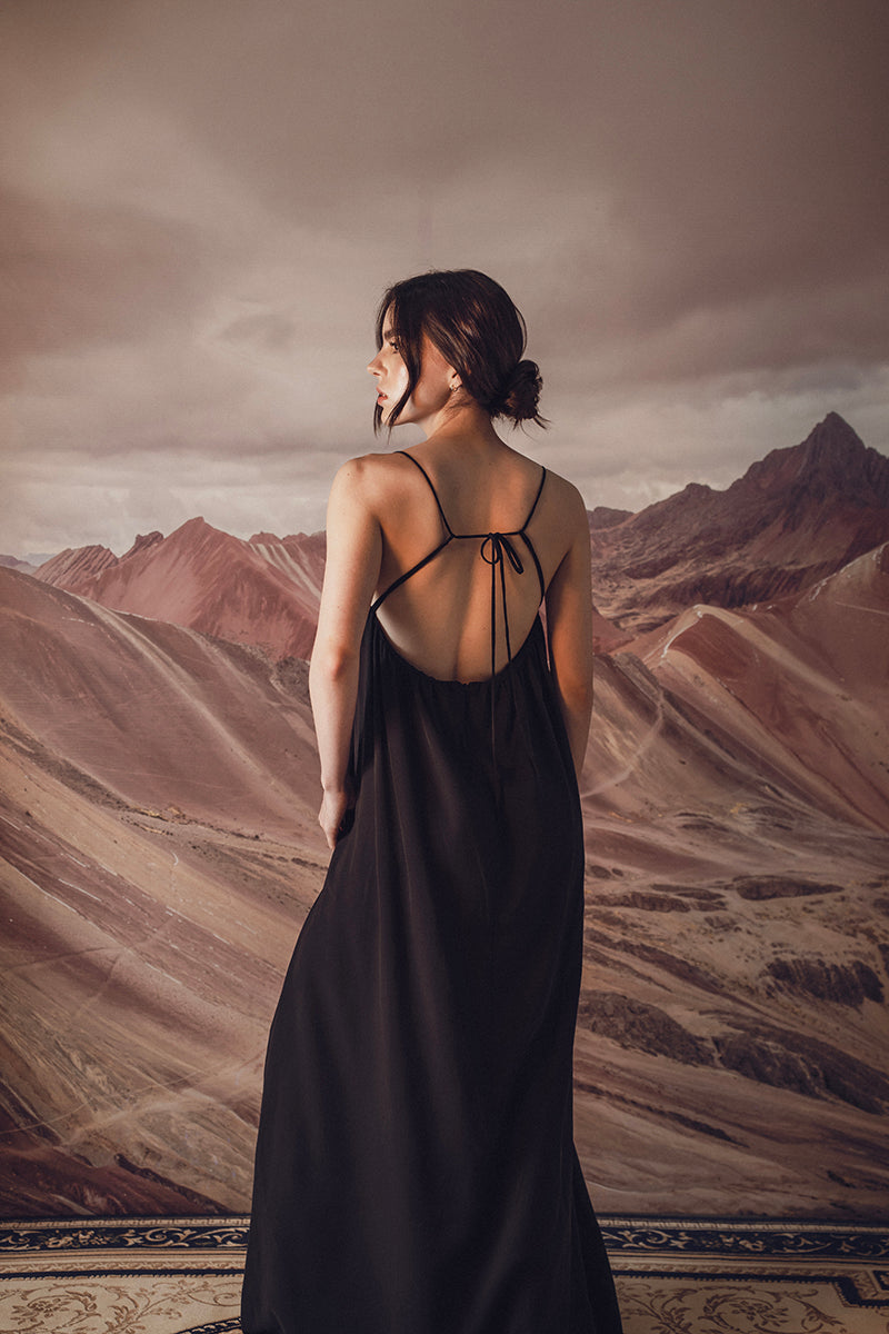 DUMA&CO Resonancia maxi dress in flowing fabric with a vibrant pattern, styled with a waist tie and long sleeves.