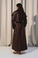 Dark brown vegan leather trench coat by Kris Marán, stylish and sleek, shown hanging on a minimalist clothing rack.