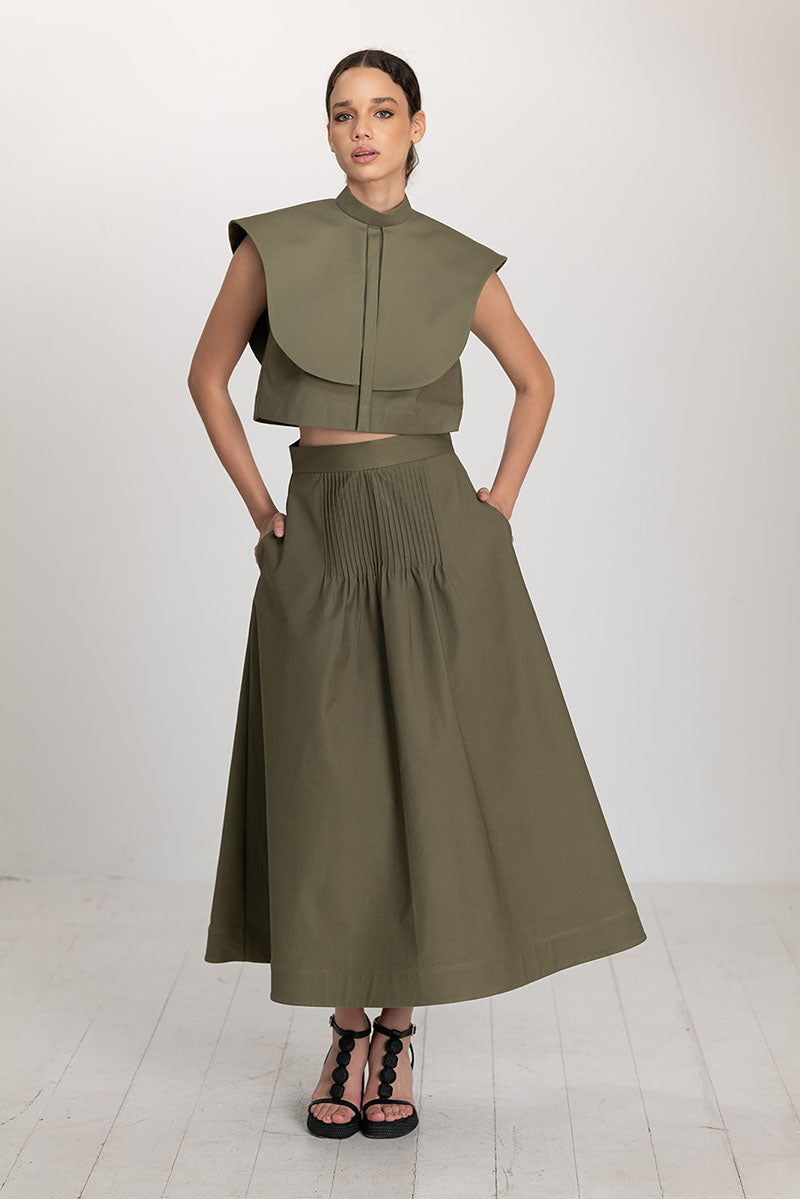 Olive drab Ana + Maria Vestal cropped top displayed on a model, featuring a fitted design and stylish neckline.