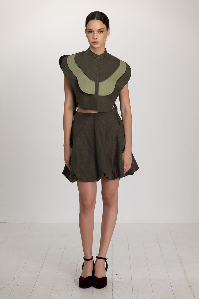 Ana + Maria Vivra bib in lichens green and sage green, showcasing a stylish, eco-friendly bib top with adjustable straps.