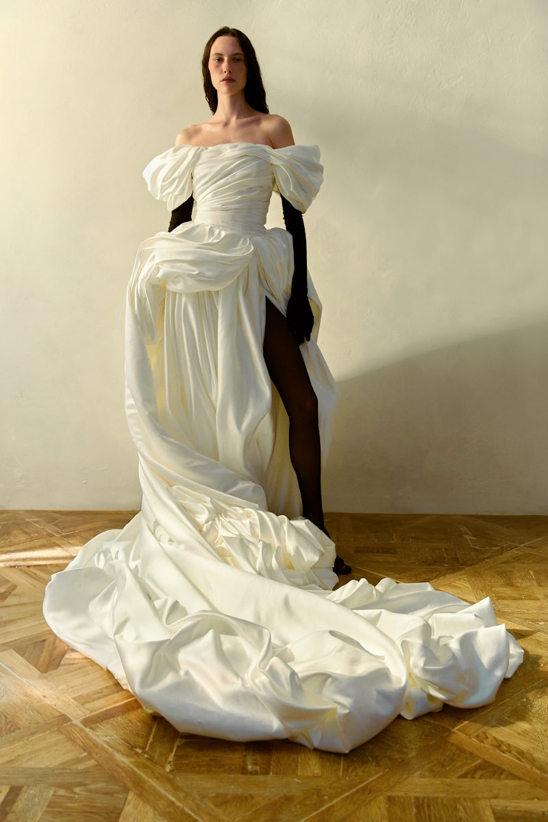 Elegant Monetre Venera Blanche gown displayed on a hanger with flowing fabric and intricate detailing.