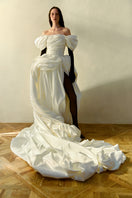 Elegant Monetre Venera Blanche gown displayed on a hanger with flowing fabric and intricate detailing.