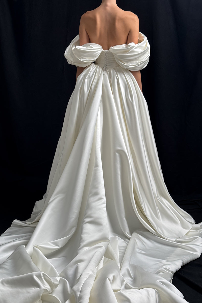 Off-white Monetre Grace gown displayed on a hanger, featuring elegant fabric and detailed design for formal occasions.
