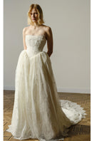 Elegant pale gown from Monetre's Agness collection, displayed hanging with flowing fabric and detailed neckline.